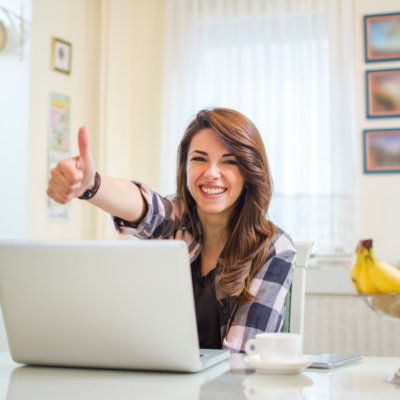 Happy confident entrepreneur working with a laptop gesturing thumbs up looking at camera.